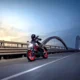 Yamaha MT-125 2027 v zákrute na moste za súmraku