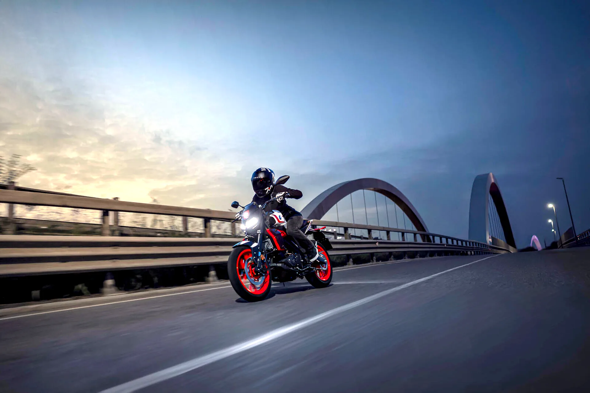 Yamaha MT-125 2027 v zákrute na moste za súmraku
