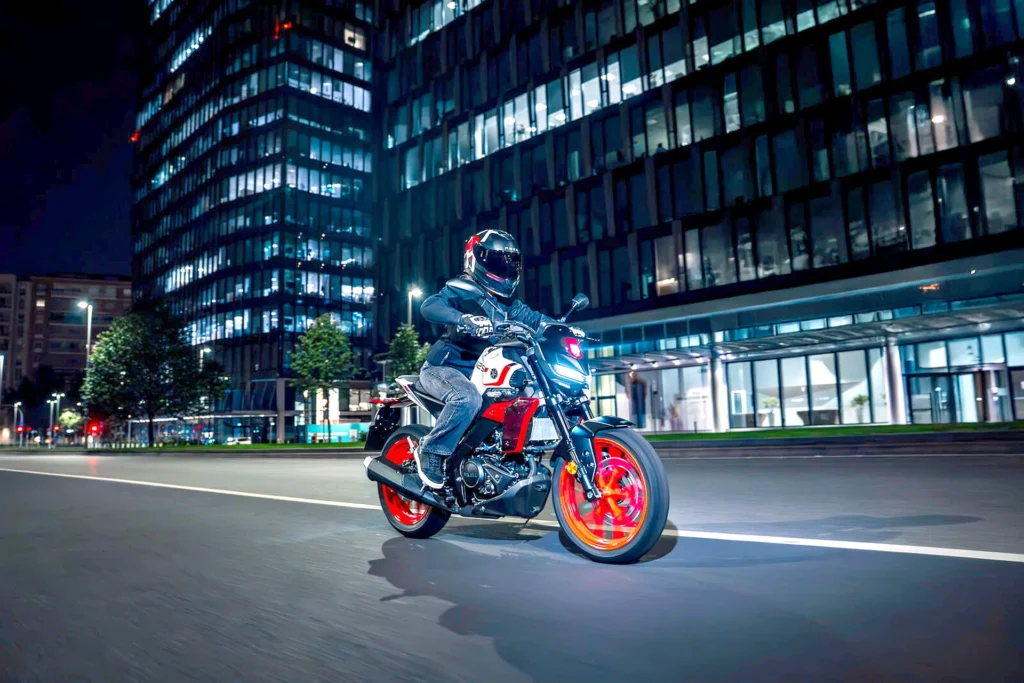 Yamaha MT-125 2027 v nočnom meste pri jazde okolo kancelárskych budov